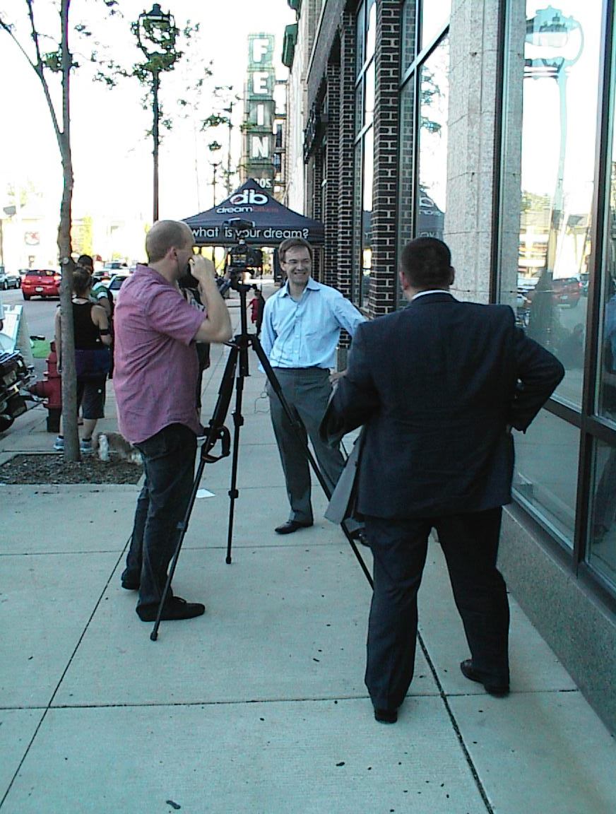 County Executive Chris Abele is interviewed outside Dream Bikes while aide Josh Zapfel (back to camera) looks on during Dream Street 2013.