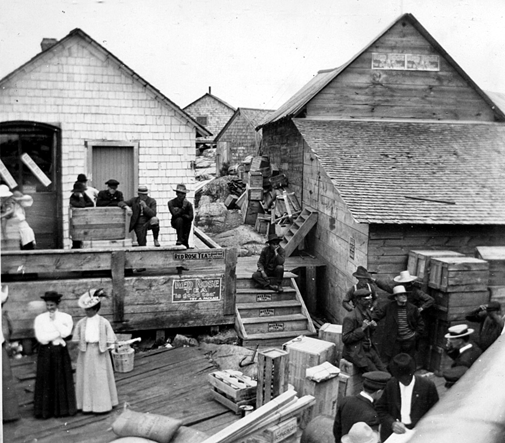 As seen on the official Wikipedia entry (credit: Salvarsan606), this 1912 scene is at the ferry landing where schoolteachers are waiting to go home for the day. 