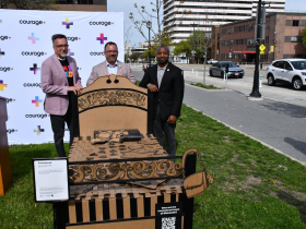 MIAD President Jeff Morin, Courage+ ED Brad Schlaikowski and Mayor Cavalier Johnson Pose With 'Unsheltered' Bed