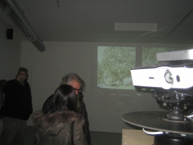 The projector (l) immerses the gallery attendees into a domestic scene that wraps around the room and undergoes subtle changes. 
