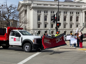 One of a dozen snowplows from across Wisconsin honks in support as it passes demonstrators with signs supporting SB 52 on March 19, 2024 outside the State Capitol