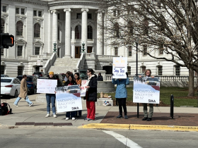 Demonstrators hold signs urging Governor Evers to sign SB 52 during the 