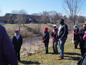 Catie Petralia listens to State Representative Supreme Moore Omokunde (D-17) along the banks of Lincoln Creek in the 17th Assembly Distric