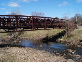 People gather on a bridge spanning Lincoln Creek near 47th and Congress streets in Milwaukee during a walk to celebrate Harriet Tubman Day on March 9, 2024