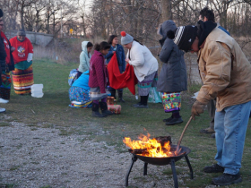 A firekeeper from Strong Native Minds tends the fire before sunrise in Lincoln Park