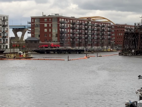 Floating booms surrounding Area of Concern dredging in the Milwaukee River in the Third Ward in April 2023