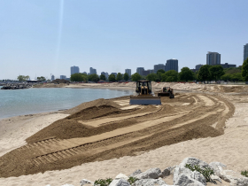 Heavy equipment pushes new sand out toward the breakwaters