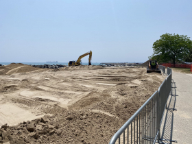 A skid steer moves sand along the west side of the beach