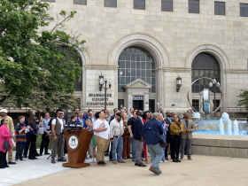 Officials and community members look on at Pride flag