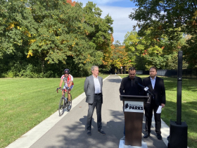 A cyclist zooms past press conference for new Underwood Creek Trail