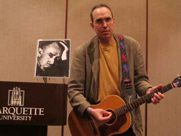 Author-Actor-Educator Paul McComas performs Bruce Springsteen’s stirring “The Ghost of Tom Joad,” inspired by “The Grapes of Wrath.” To his right is a photo of John Steinbeck. (Photo by Jennifer Reinke)