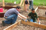 Two volunteers fit together the lumber for a raised garden bed. (Photo by Amalia Oulahan)