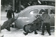 Passing good samaritans hop of their bikes to help push a car out of the snow.