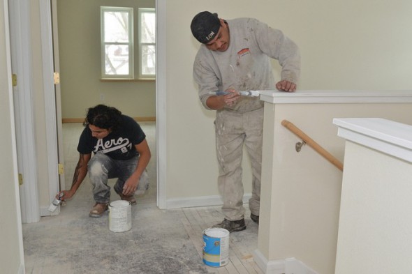 Ricardo Avila and Rodolfo Garcia add a fresh coat of paint to the interior of the renovated home on South 33rd Street. (Photo by Sue Vliet)