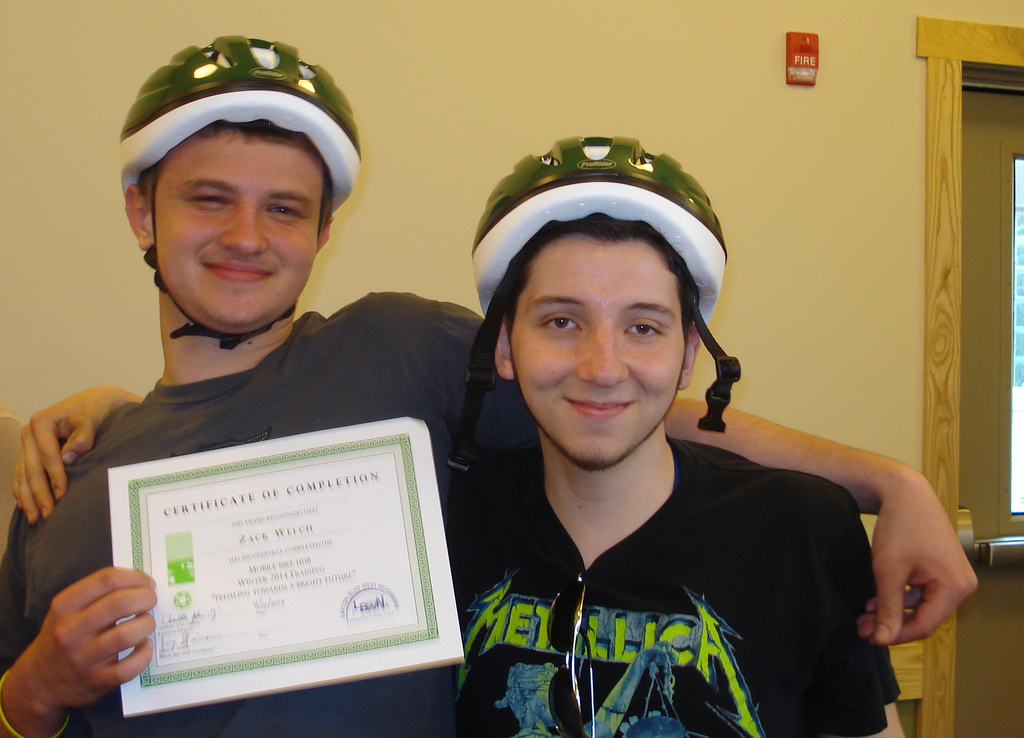(From left) Participants Zack Welch and Cesar Becerra show off their helmets and certificates after the graduation ceremony. (Photo by Kelly Meyerhofer)