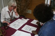Anita Johnson (right) takes Janice Erickson through a list of voter ID requirements, as outlined by the Milwaukee Election Commission. Photo by Jabril Faraj.