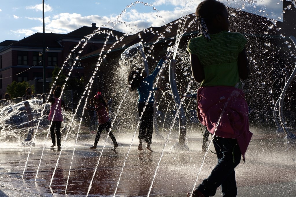 Neighborhood youth play in the splash pad after opening ceremonies for the renovated Moody Park. Photo by Adam Carr.