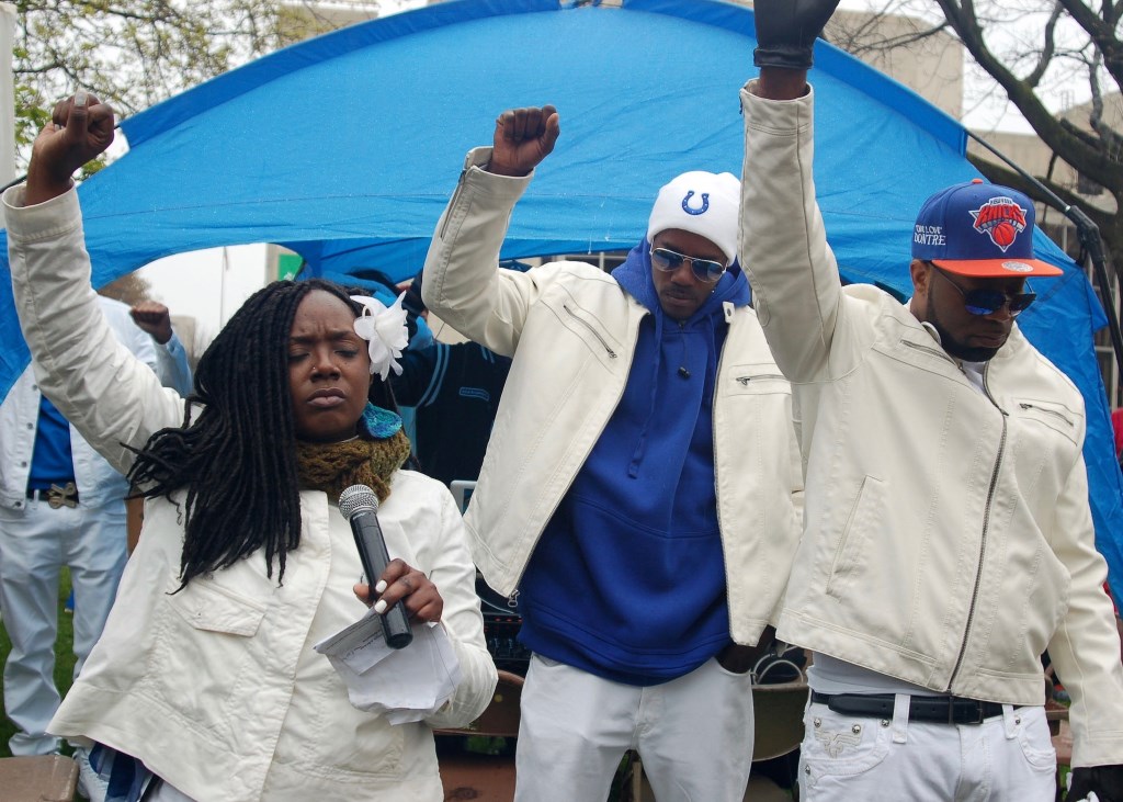 (From left) Markasa Chambers, a member of the Coalition for Justice, and brothers Nate Hamilton and Dameion Perkins lead supporters in 14 seconds of silence, symbolizing the 14 bullets that felled Dontre Hamilton two years ago. Photo by Andrea Waxman.