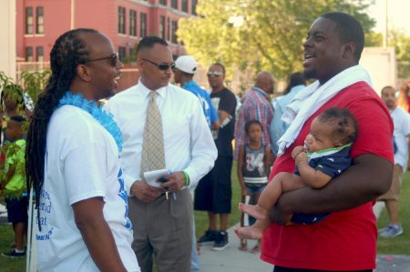 Brandon Brown (right), holding his 4-month-old-son Brandon Jr., chats with Dennis Walton (left), co-director of the Milwaukee Fatherhood Initiative. Photo by Edgar Mendez.