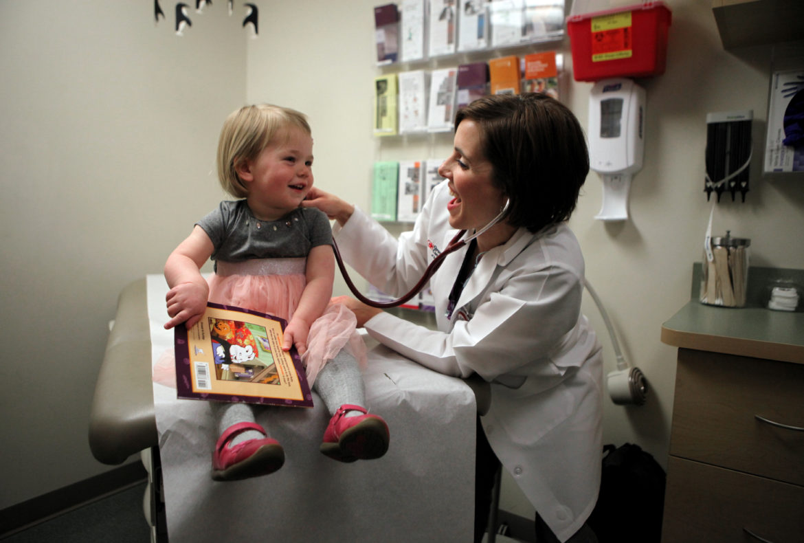 Hannah Tunney, 2, holds a book while getting a check-up from nurse practitioner Francesca Vash at Group Health Cooperative health care center in Madison. GHC participates in the national Reach Out and Read program, which distributes books to children up to age 5 at each regular check-up. The program is designed to encourage families to develop good reading habits. Photo by Coburn Dukehart of the Wisconsin Center for Investigative Journalism.
