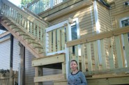 Maria Alvarado stands at the base of the staircase and upper deck built with funds provided by the Department of Neighborhood Service’s Code Loan Program. Photo by Edgar Mendez.