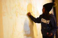 Tia Richardson traces the outline of a mural she is working on at All People’s Church. Photo by Brittany Carloni.