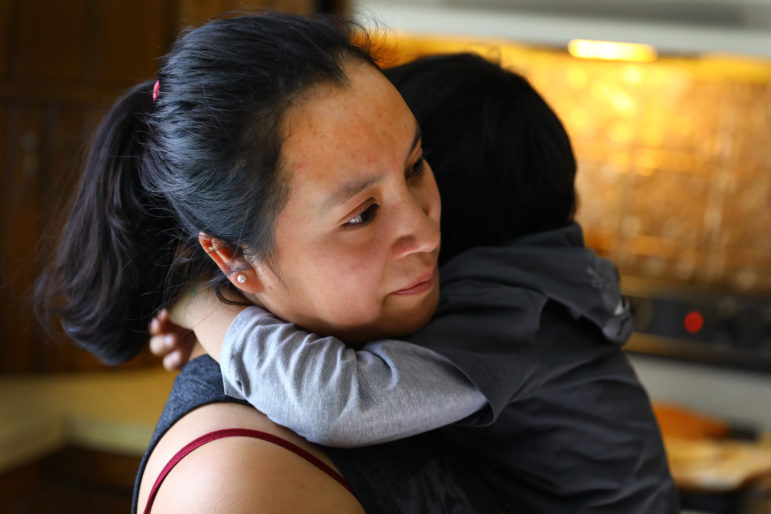 "Rosa" hugs her 3-year-old son at their home on a dairy farm in Pepin County, Wis. Her husband, "Manuel" is a laborer on the farm. She says her family has experienced racial slurs since President Donald Trump took office. Photo by Coburn Dukehart of the Wisconsin Center for Investigative Journalism.