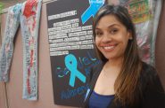 Eileen Alvarado, author and youth advocate, stands next to a “Demin Day” display at the UMOS Latina Resource Center. Photo by Edgar Mendez