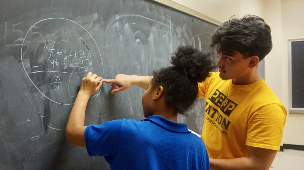 PeppNation Youth Development Mentor Marco Sweeti, a student at UW-Milwaukee, tutors middle school students at Benjamin Franklin School. Photo by Bridget Fogarty/NNS.