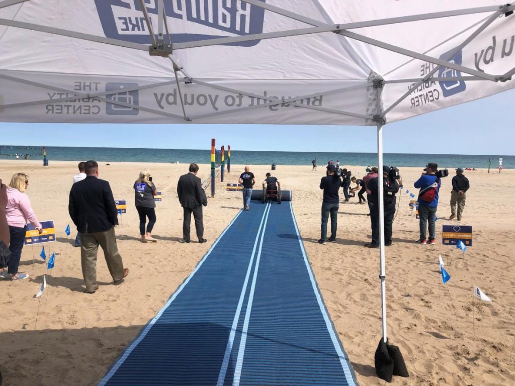 Unrolling a Mobi-Mat at Bradford Beach in Milwaukee June 3. Photo from The Ability Center.