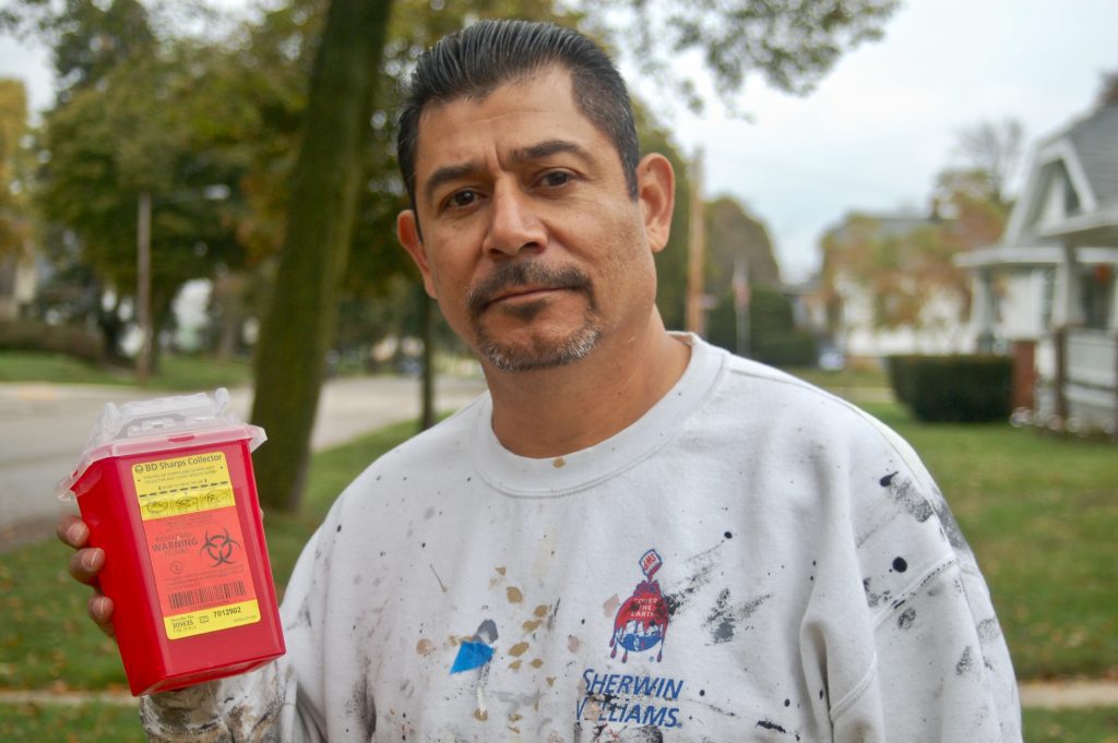 Rafael Mercado, founder of Team HAVOC, holds a container of needles collected during a cleanup on the South Side. (File photo by Edgar Mendez)