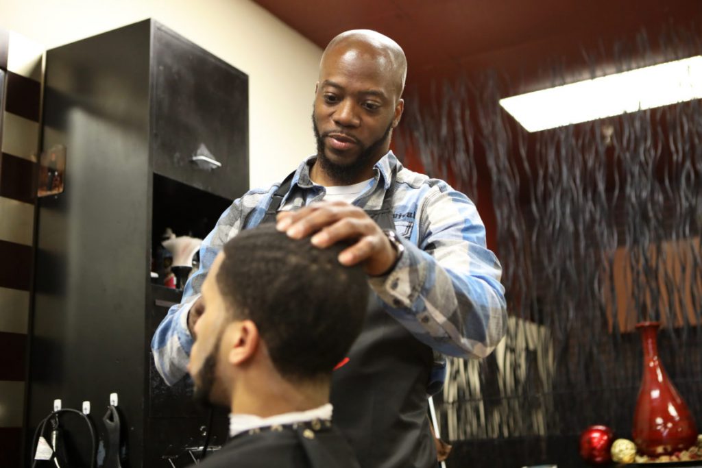 Brian Britt cuts the hair of DeUndre Moore at the Inspire Barber and Beauty Salon, which he owns, in Madison, Wis., on May 8. Britt opened the salon in 2017 and said he had difficulty finding a space to rent due to having a number of convictions on his record, including possession with intent to deliver marijuana in 2000. Photo by Coburn Dukehart/Wisconsin Watch.