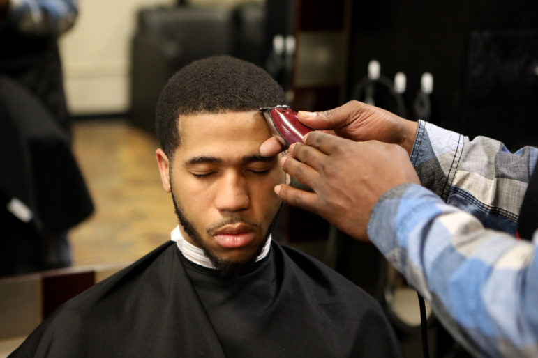 Brian Britt cuts the hair of DeUndre Moore at the Inspire Barber and Beauty Salon, which he owns, in Madison, Wis., on May 8. Britt says he spent five years in prison and has seen firsthand how challenging it is for someone with a criminal record to attend school or start a business. Photo by Coburn Dukehart / Wisconsin Watch.