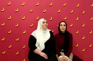 Nayfa Naji (left) and Amal Azzam pose in front of the banana wall during Fanana Banana’s second art show in Walker’s Point in November. Photo by Claudia Delgadillo/NNS.