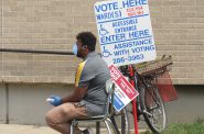A poll worker sits outside of Washington High School wearing a protective mask. Photo by Isiah Holmes/Wisconsin Examiner.