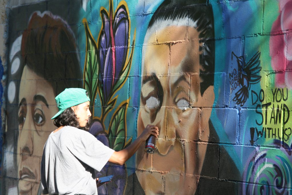 Aisha Valentin paints Supreme Court Justice Thurgood Marshall in a civil rights mural in Harambee. Photo by Jeramey Jannene.