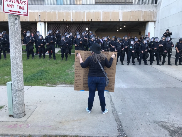A protester holds a sign up to law enforcement gathered outside the city of Milwaukee's Police District One building on Sunday, May 31, 2020. Madeline Fox/WPR.