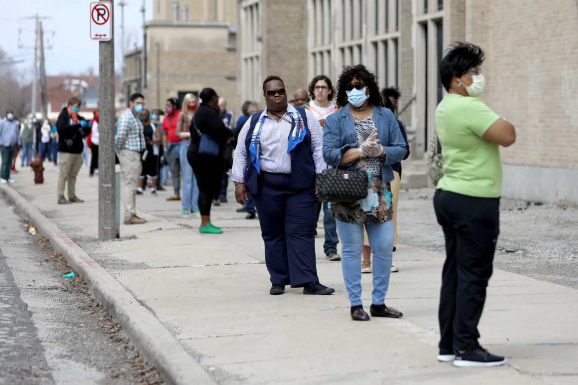 Voters waited for hours in long lines to vote in Milwaukee on April 7, 2020. Here, the voting line wraps around the block outside Washington High School. Researchers say that consolidating polling sites and health concerns of voting in-person during the pandemic kept many Milwaukee voters away, especially Black residents. Photo by Coburn Dukehart/Wisconsin Watch.