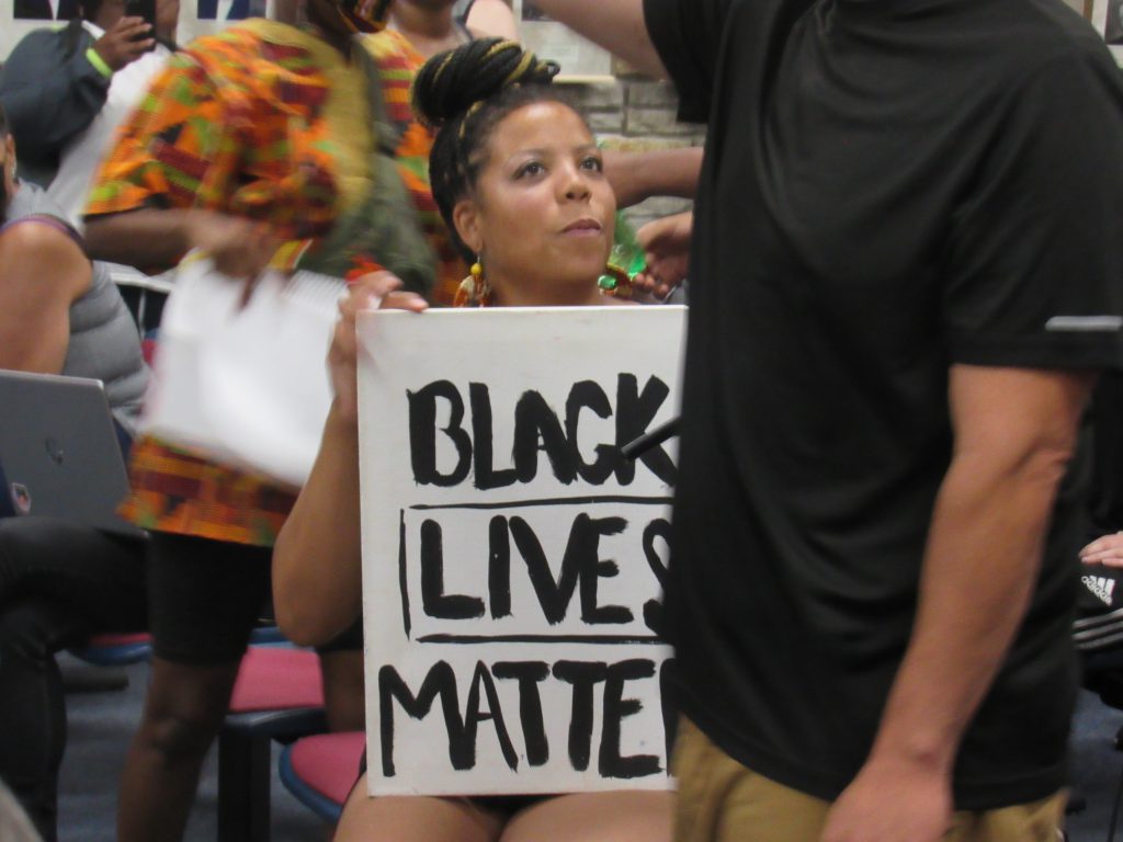 A Black Lives Matter protester attending a Wauwatosa City Council meeting. Protesters had been marching to get officer Joseph Mensah fired for killing three people in five years. Photo by Isiah Holmes/Wisconsin Examiner.