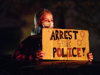 A protester holds a sign as she stands in the open sunroof of a vehicle Wednesday, Oct. 7, 2020, near Wauwatosa. Angela Major/WPR