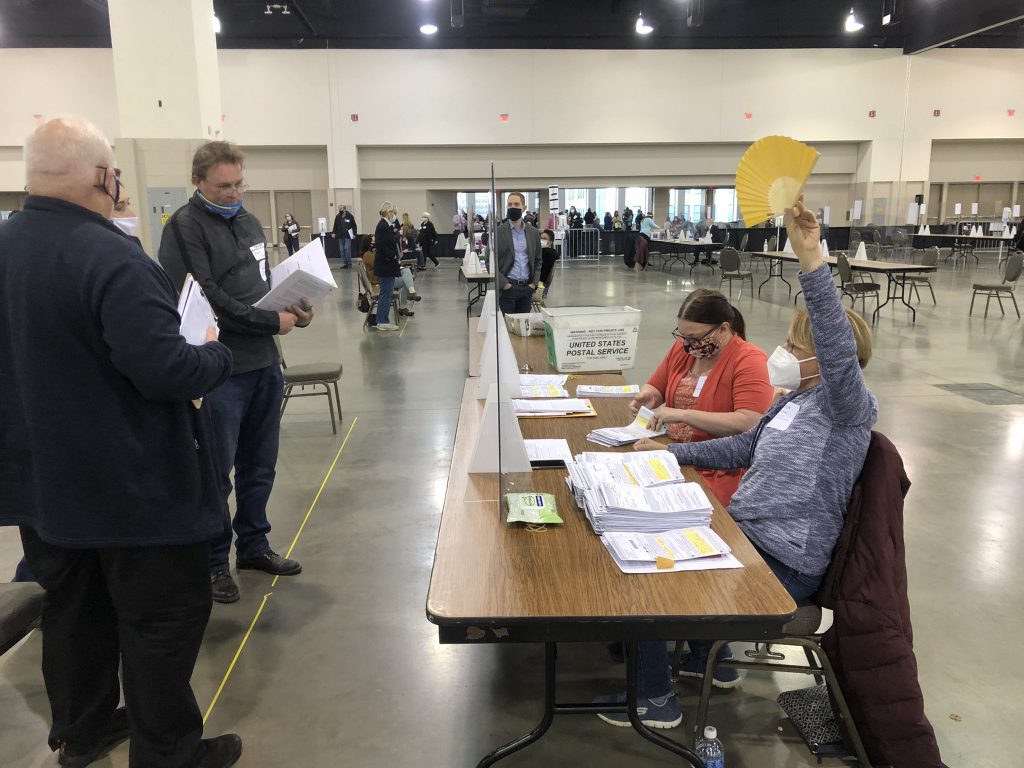 A City of Milwaukee poll worker raises her marker for clerk support while a Trump campaign observer objects to a absentee ballot envelope during the 2020 presidential recount. Photo by Jeramey Jannene