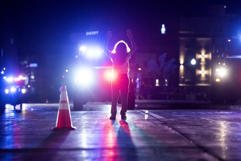 A protester stands in front of bearcats as people are cleared out of the area Wednesday, Aug. 26, 2020, in Kenosha. The protests were in response to police shooting and wounding Jacob Blake. Angela Major/WPR