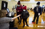 Makaila Arrington, 7, center, gets a sticker from a poll worker while standing with her mother, Crystal Arrington, and her brother, Jacen, right, on Nov. 3, 2020, at Fifty-Third Street School in Milwaukee. Activists worked hard to engage Milwaukee voters ahead of the election but overall turnout in the city was the same as 2016. Angela Major / WPR