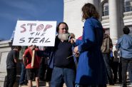 A supporter of President Donald Trump holds a sign as he speaks to a reporter Saturday, Nov. 7, 2020, in front of the Wisconsin state Capitol. Angela Major/WPR