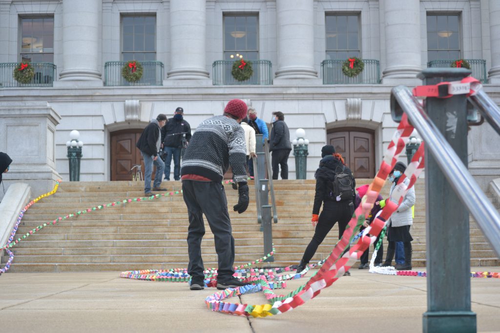 Volunteers array strands of an 833-foot paper chain on the steps of the state Capitol Wednesday, commemorating Wisconsin residents who died from COVID-19. Photo by Erik Gunn/Wisconsin Examiner.