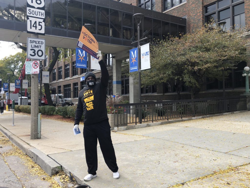 Cy Cullen waves at passersby while volunteering at a When We All Vote event on Oct. 24, 2020. Organizers offered attendees pamphlets on where and how to vote, as well as free food, at the event outside of the Fiserv Forum in Milwaukee. Nora Eckert / Wisconsin Watch