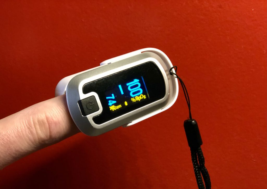 A pulse oximeter shows a blood oxygen level of 100% and a pulse of 74 beats per minute. Lower oxygen levels could signal that a COVID-19 infection is worsening. Healthy people typically have blood oxygen levels around 98% or 99%, says Dr. Michael Landrum, an infectious disease physician at Bellin Health in Green Bay, Wis. Patients who take several slow, deep breaths and still register a blood oxygen level at or below 94% should call their doctor or seek care at a clinic, Landrum says. Jim Malewitz / Wisconsin Watch