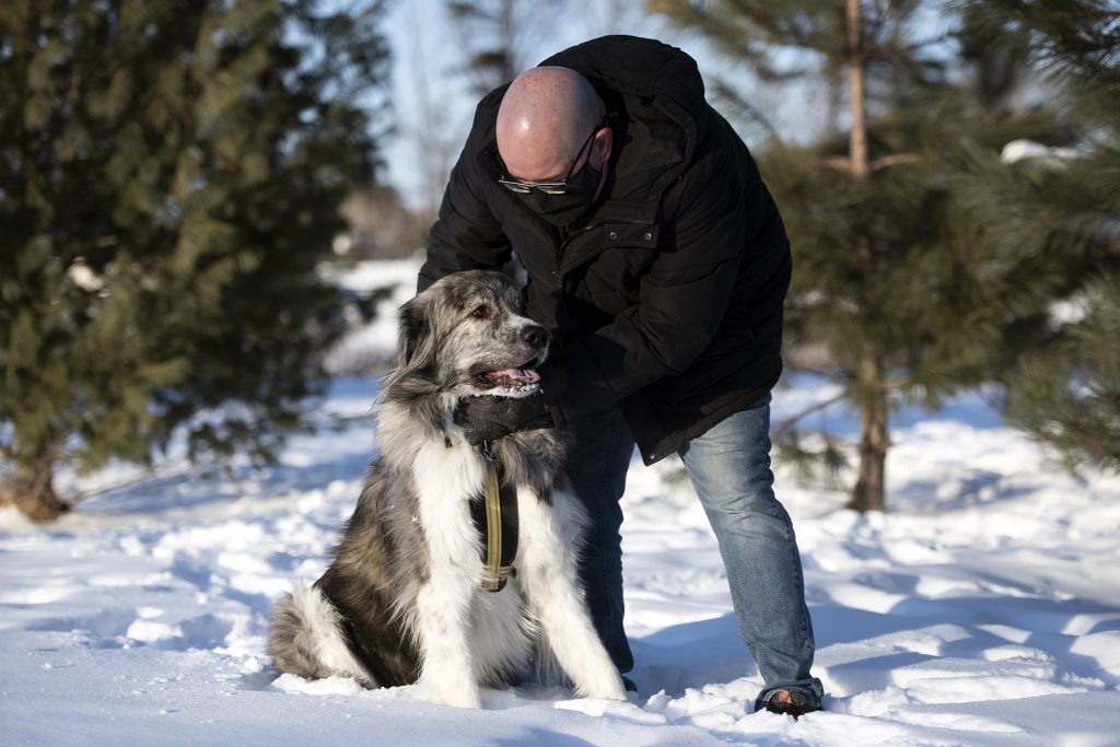 Paul Mathis pets his dog, Tiberius, at the dog park, on Feb. 16, 2021, in Wausau, Wis. Mathis is a “long-hauler,” someone whose COVID-19 symptoms have lasted for months. Photo by Angela Major/WPR.
