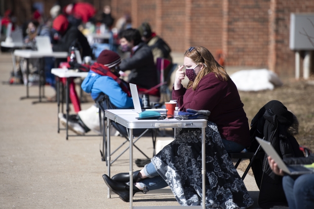 A teacher teaches virtually from outside La Follette High School on Thursday, March 4, 2021, in Madison, Wis. Teachers from the high school held the outdoor demonstration to raise concerns about lack of access to COVID-19 vaccines. Angela Major/WPR