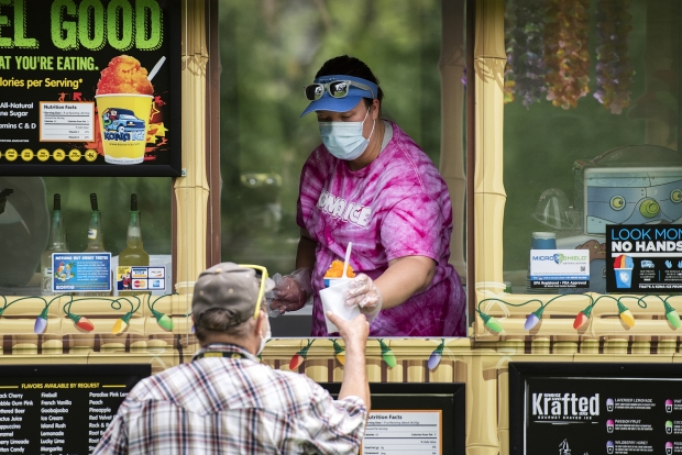 Amber Krueger, a driver for Kona Ice, wears a mask as she serves frozen treats to customers Tuesday, July 21, 2020, in Janesville, Wis. Angela Major/WPR